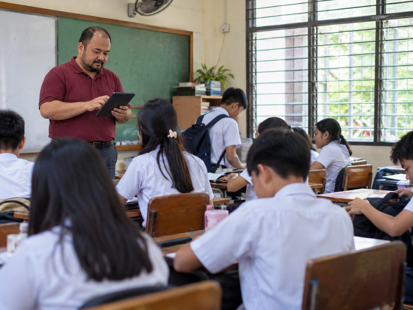 An adviser checking names on a tablet at the front of his homeroom as students settle into their seats.
